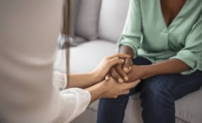 Person holding another's hands in a comforting gesture