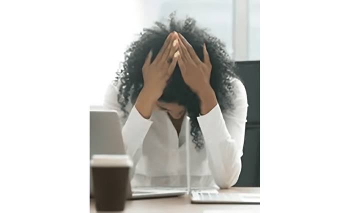 Person at a desk holding their head in frustration