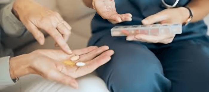 Hands holding pills and a pill organizer
